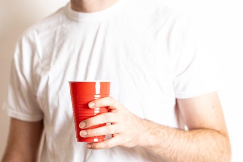 Person holding a red disposable party cup on a white background