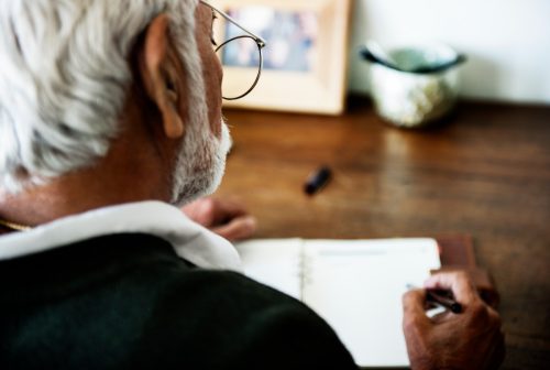 older man writing in journal