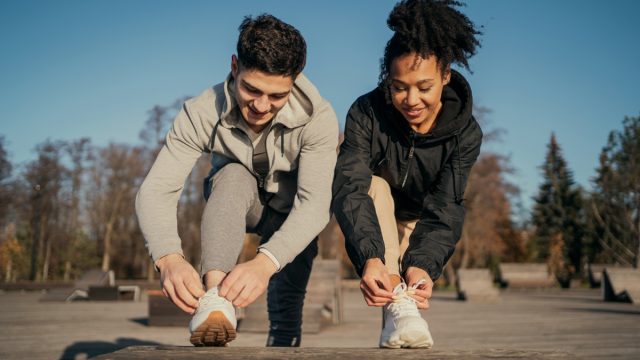 man and woman adjusting sneakers before a walk