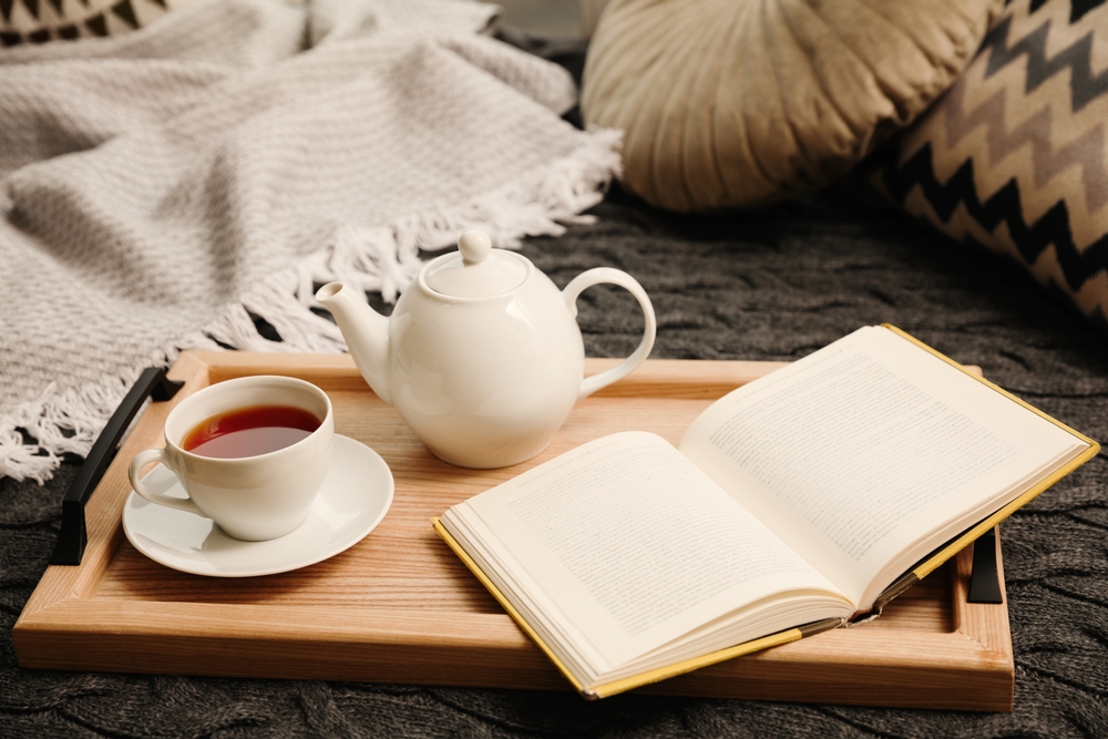 Cozy decor with book and tea pot or coffee and throw blanket in reading nook