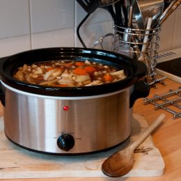 Slow cooker with vegetables inside sitting on a kitchen counter
