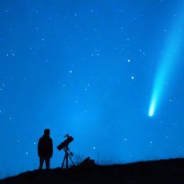A person stargazing and watching a comet with a long tail in the night sky