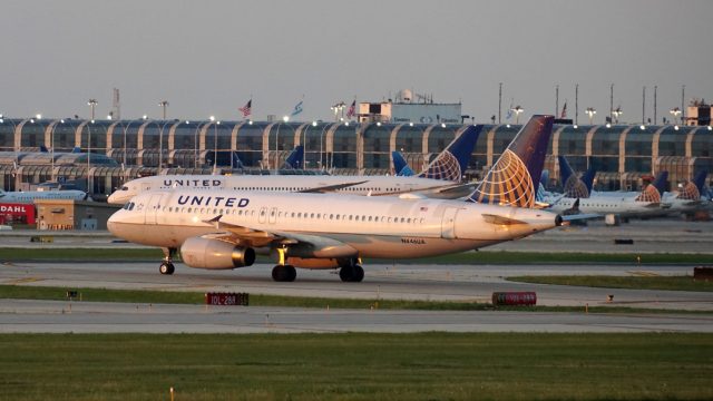 A United Airlines plane sitting on the runway at the airport with more United planes in the background