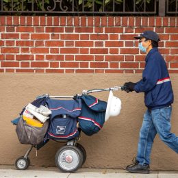 San Francisco, USA - April 4, 2020: San Francisco postal worker in mask delivering mail during stay-at-home order.