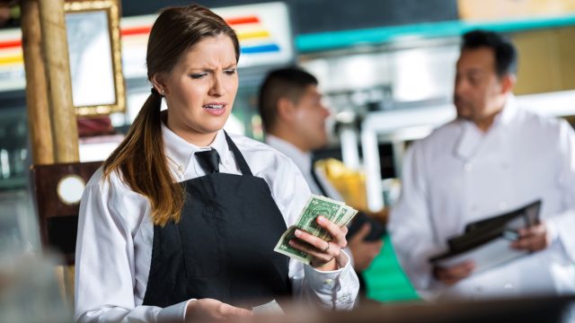A server looking at money with a disappointed expression due to a bad tip