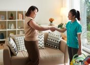 woman shaking hands with cleaning service worker to thank her for her work while they standing in living room