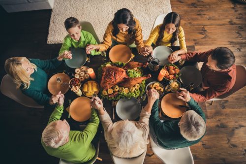 Aerial view of family holding hands at a Thanksgiving table