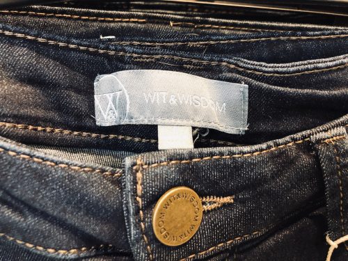 Close up of the Wit and Wisdom jeans label on a pair of women's skinny blue jeans.