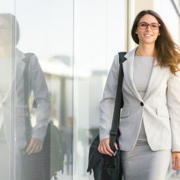 Female businesswoman in beige suit walking next to building