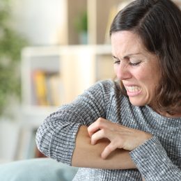 Middle age woman scratching itchy skin at home