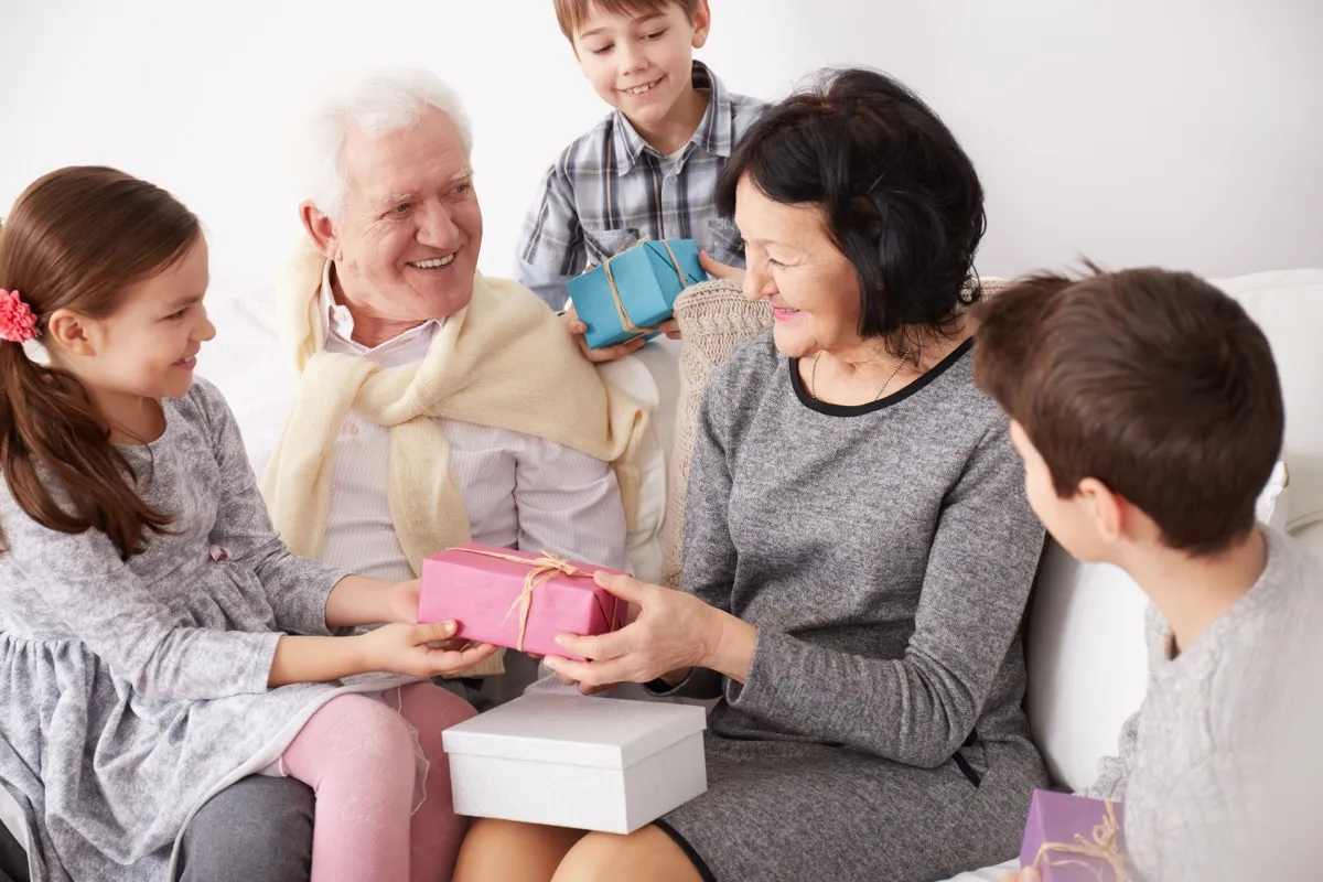 Happy grandchildren giving surprise presents to their beautiful grandparents