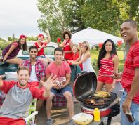 Friends cheering at tailgate barbecue in field