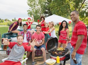 Friends cheering at tailgate barbecue in field