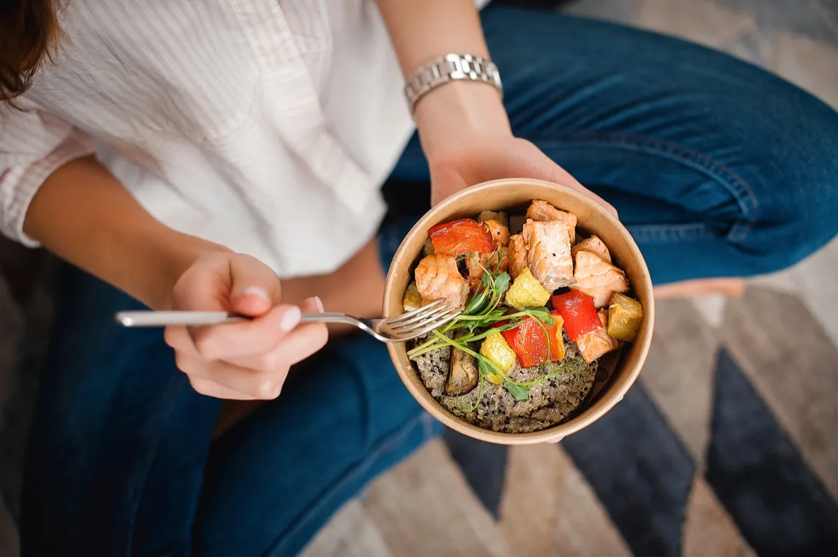 Woman eating small bowl of healthy food