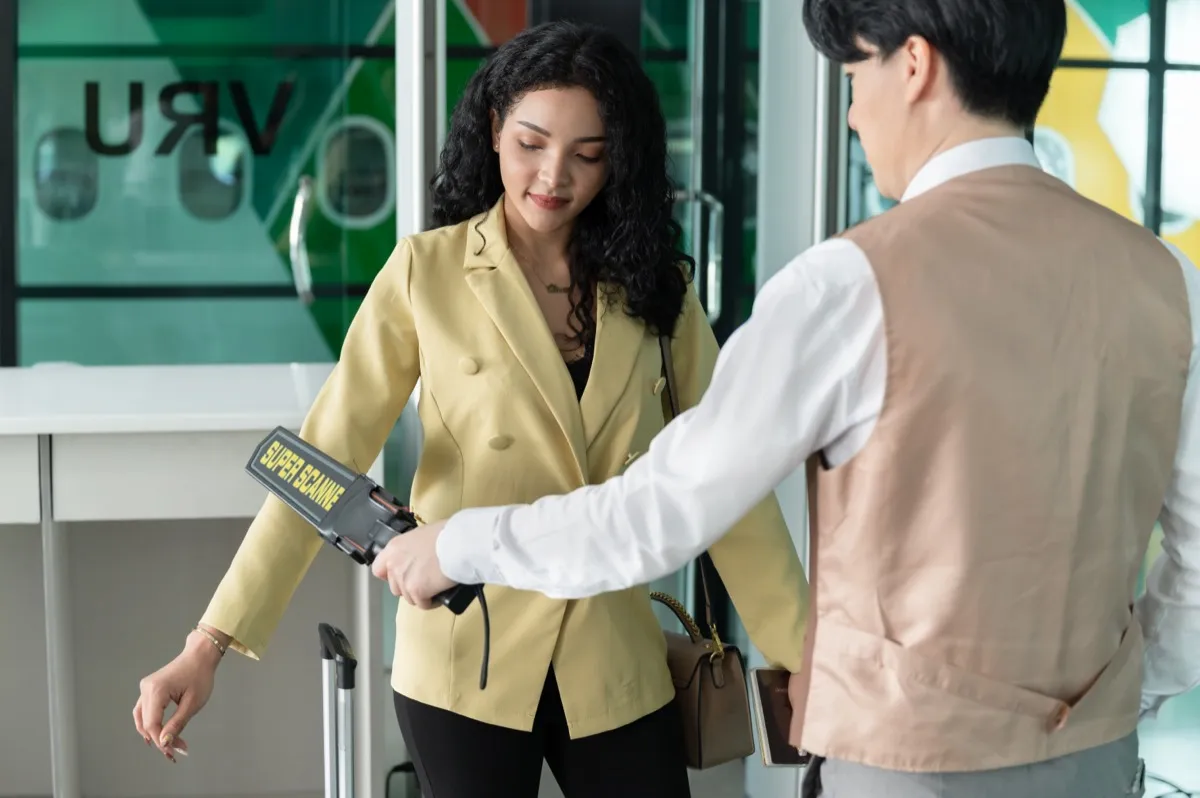 Businesswoman going through procedure of physical inspection and luggage scanning in airport