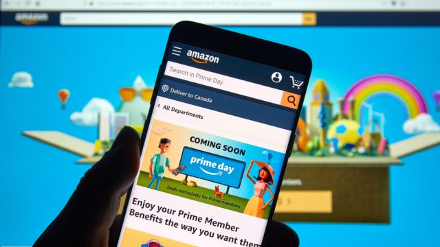 A close up of a phone with the Amazon Prime Day advertisement on it in front of a comptuer screen