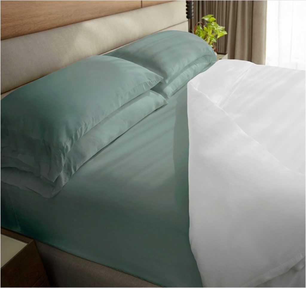 A set of Tahitian Breeze colored Cariloha Bamboo Bed Sheets on a mattress with a white comforter