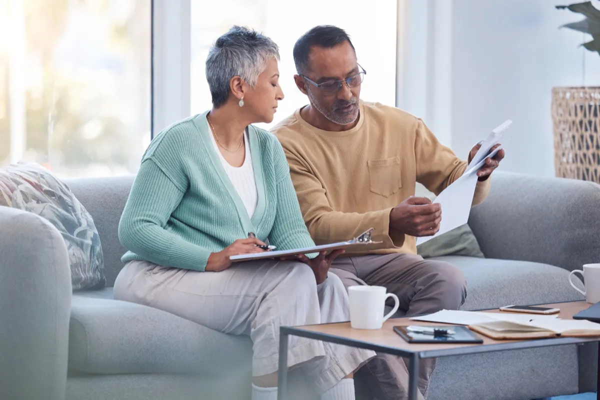 Mature couple sitting on their couch looking through documents