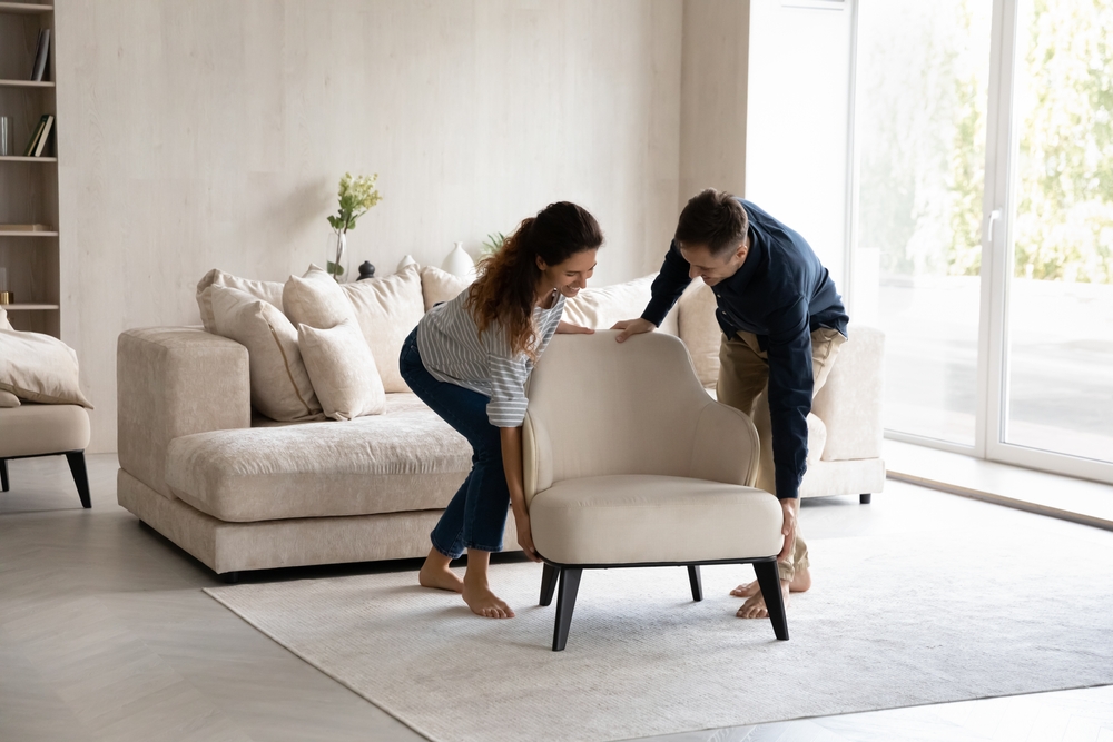 A couple moving a modern armchair in their living room