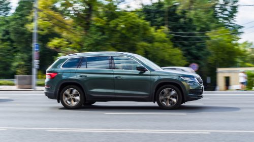 View of a dark green SUV driving on the road