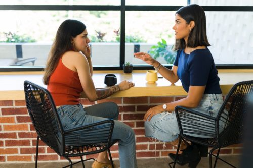 two women having a serious conversation at a coffee shop