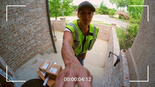 Packages being delivered to a home, as seen from a security camera.