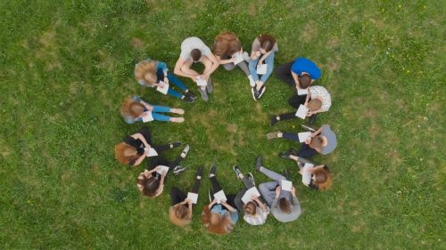 group of adults sitting in a circle outside playing a game