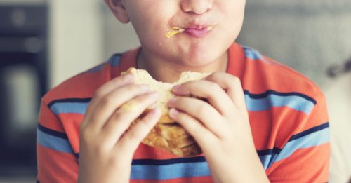 little boy taking a big bite out of a sandwich
