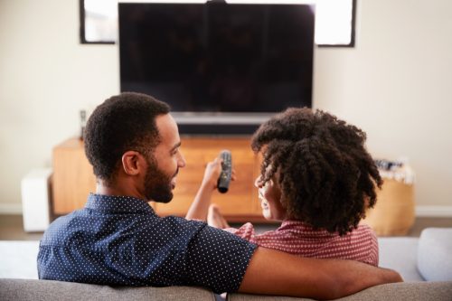 man and woman embracing as they watch television