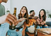 group of friends laughing over funny questions while eating popcorn and drinking beer