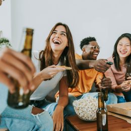 group of friends laughing over funny questions while eating popcorn and drinking beer