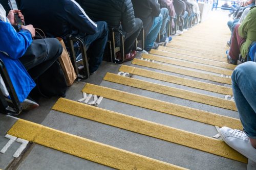 People sitting seats number with staircase down to the stadium field. Numbered steps in a sport stadium in between the people seating.
