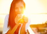 smiling woman drinking coffee in the sunlight