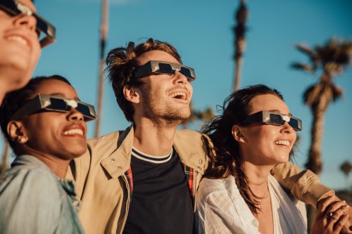 A group of people watching a solar eclipse while wearing protective glasses