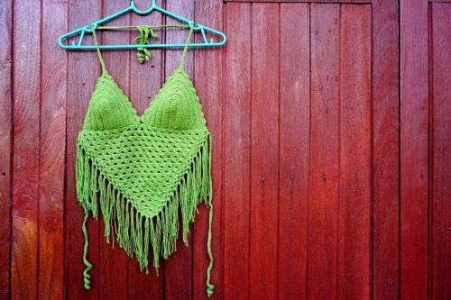 Green bikini top hang on brown wood background, summer beach and holiday concept