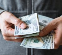 A close up of hands holding $100 bills