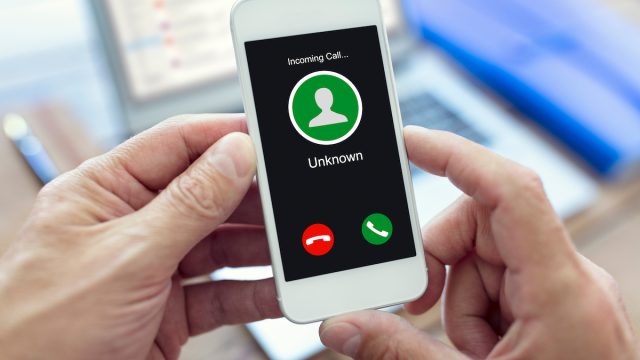 Incoming call with unknown number on mobile phone held by hands.