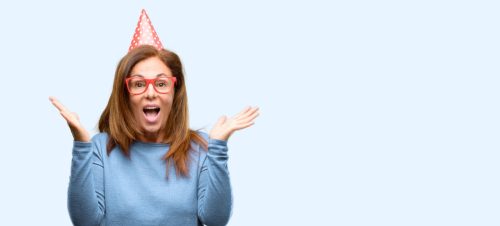 Middle age woman celebrates birthday happy and surprised