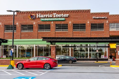 Sign for Harris Teeter Kroger grocery store business and blue sky in northern Virginia brick architecture parking lot