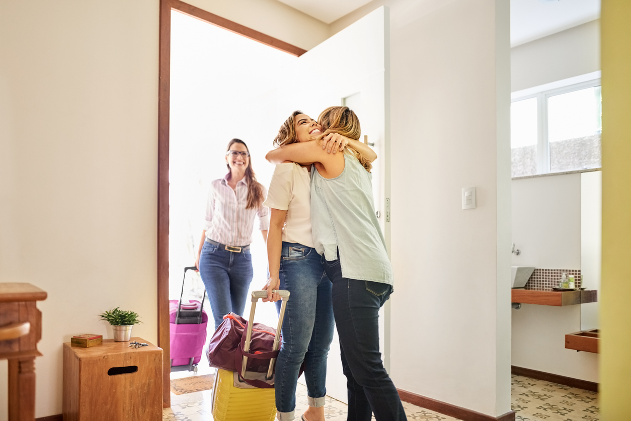 A woman greeting houseguests at her front door
