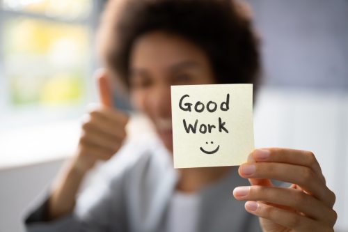 woman holding up a sticky note saying "good work"