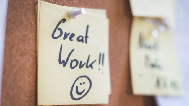 Close up of pinned note “Great work” on cork board