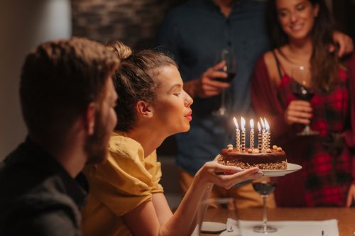 young woman blowing candles on birthday cake.