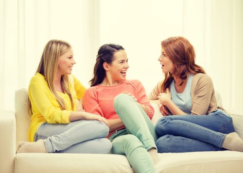 three women sitting on a couch talking