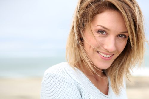 Close-up portrait of a smiling middle-aged woman with dirty blonde hair on the beach