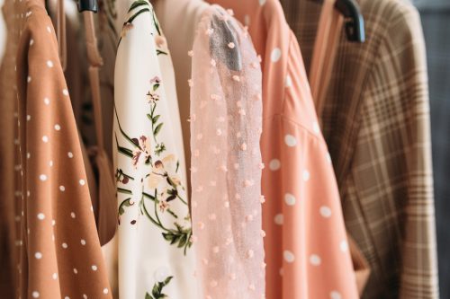 Pink and brown patterned blouses hanging in a closet