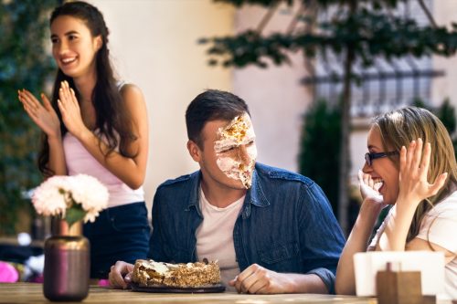 man with cake all over his face, two women laughing