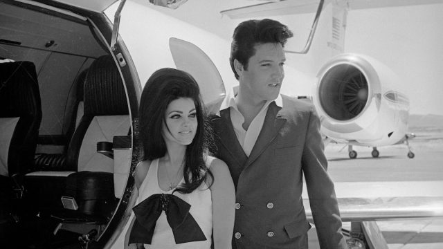Priscilla and Elvis Presley in front of a plane following their wedding in 1967