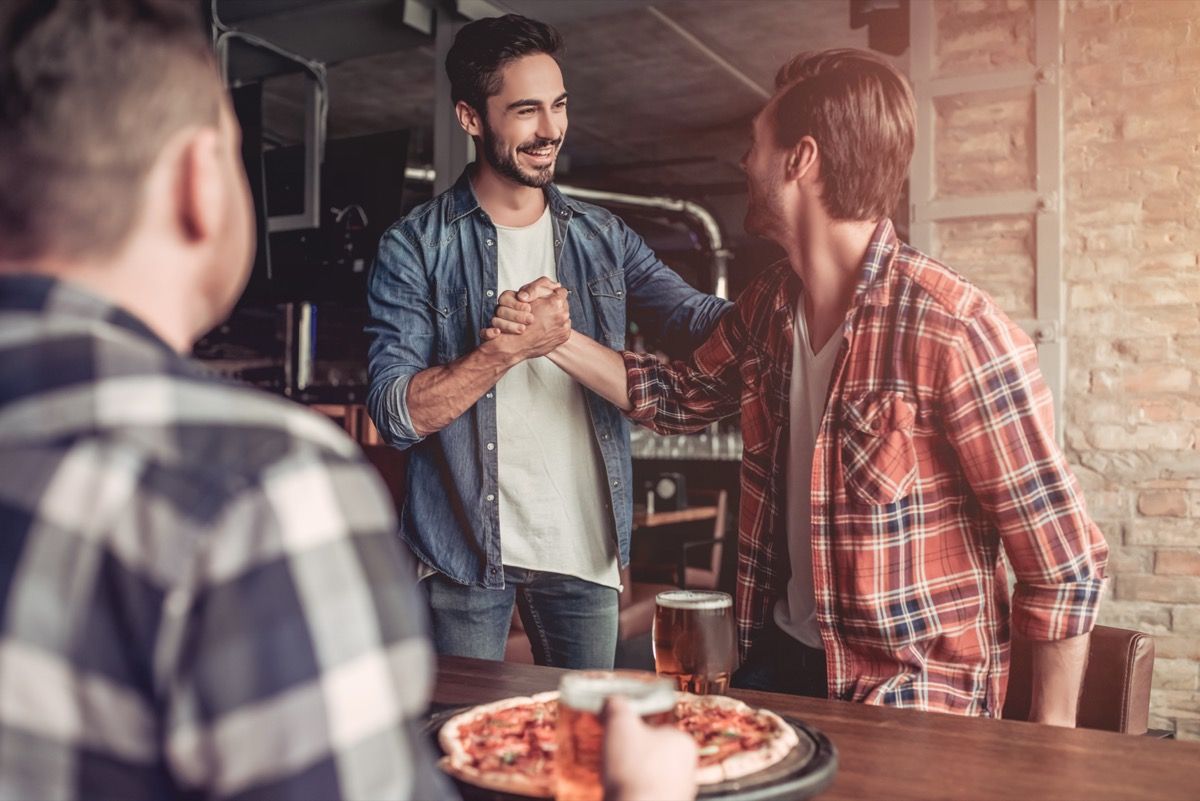 two men shaking hands in a bar