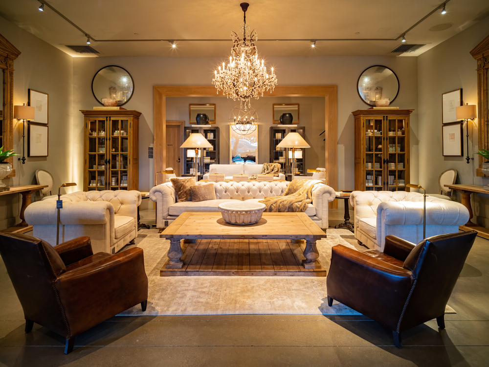 The interior of a Restoration Hardware or RH show room with chairs, a sofa, and a chandelier